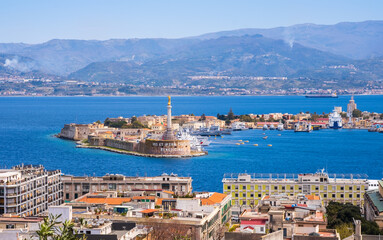 The Strait of Messina between Sicily and Italy. View from Messina town with golden statue of Madonna della Lettera and entrance to harbour. Calabria coastline in background - obrazy, fototapety, plakaty