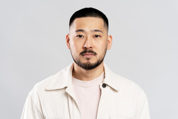 Fototapeta premium Portrait of handsome serious asian man with stylish hair, wearing casual clothes, looking at camera after barbershop service, isolated on white background