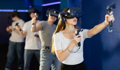 Young woman with handheld controllers in hands clearly excited and engaged in virtual world...