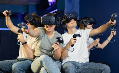 four comrades using virtual reality headset in space adventure game .Happy people sitting and having fun with new technology vr headset goggles