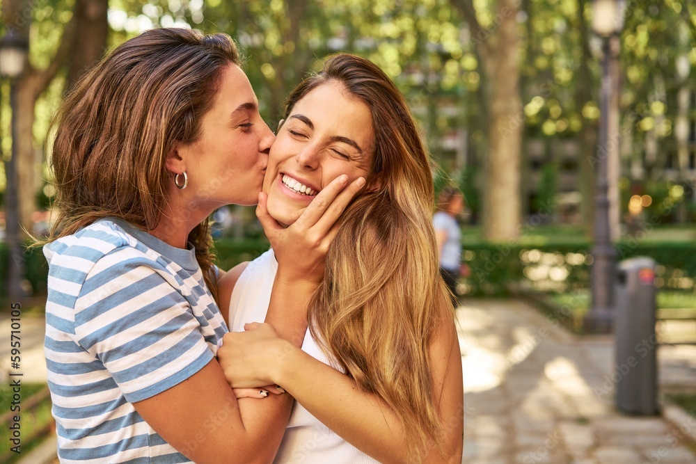 Wall mural Two friends share a kiss in a park