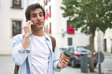 Young man masters the art of multitasking with a takeout coffee in hand and a productive phone call on his way to work.