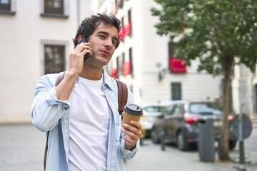 Young man masters the art of multitasking with a takeout coffee in hand and a productive phone call on his way to work.
