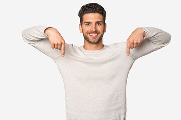 Young handsome man isolated points down with fingers, positive feeling.