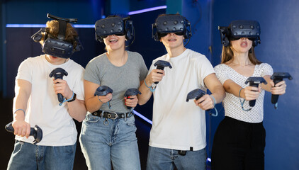 four comrades with virtual reality helmet and joysticks fight in multiplayer game. New generation...