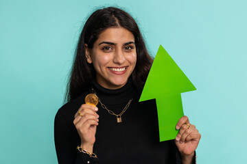 Indian woman winner holding arrow sign pointing up showing golden bitcoins, cryptocurrency...