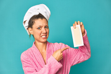 Freshly showered young Caucasian woman holding a depilatory strip.