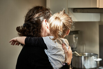 L'amour maternel enveloppant, une petite fille dans les bras de sa maman, vue de dos