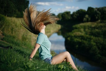 woman sitting on the river flipping her hair in summer
