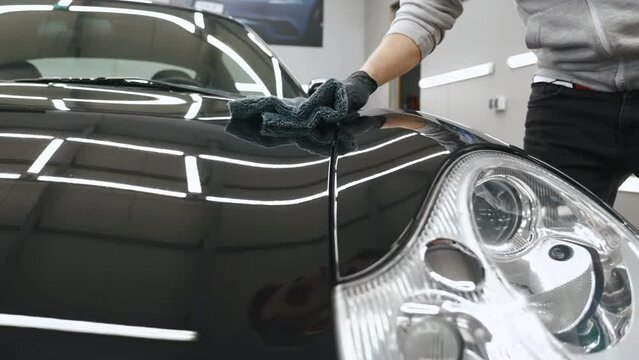 Video shot of an arm putting ceramic coating on a black car hood . High quality 4k footage