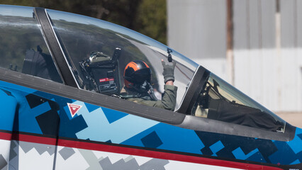 piloto de avion militar saludando con la seña de la mano cornuta o cornuda