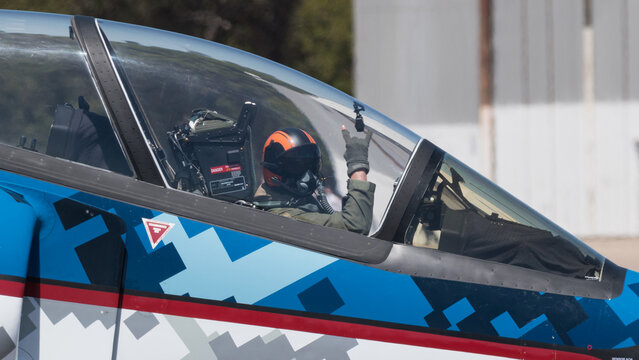piloto de avion militar saludando con la se&ntilde;a de la mano cornuta o cornuda