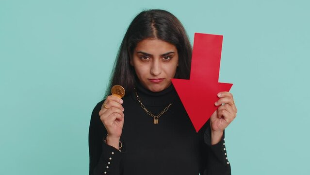Upset indian woman showing red arrow pointing down downgrade unsuccessful business, fall of cryptocurrency stock market investment, mining bitcoins BTC money exchange rate, bankruptcy fail. Hindu girl