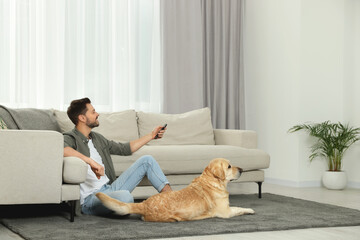 Man turning on TV near his cute Labrador Retriever at home