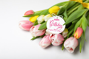 Beautiful bouquet of tulip flowers with Happy Birthday card on white background