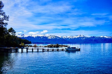 muelle y embarcación, con montañas de fondo y lago