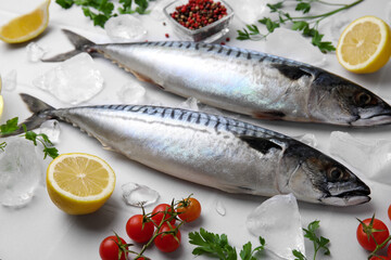 Raw mackerel, lemons and tomatoes on white table