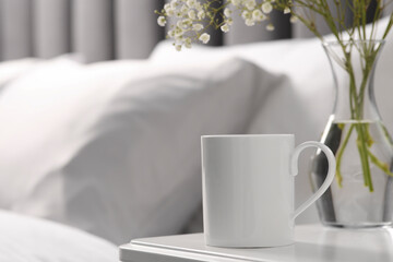 Ceramic mug on white bedside table indoors. Mockup for design