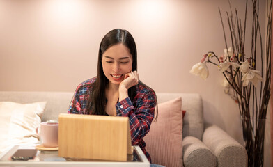 Happy satisfied Asian woman rest at the home office sitting with the laptop after finishing work and feels peaceful and relaxed.