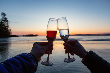 Man and Woman Cheers with Champagne Flute Glasses on the Beach at Sunset. Tofino, Vancouver Island, British Columbia, Canada.