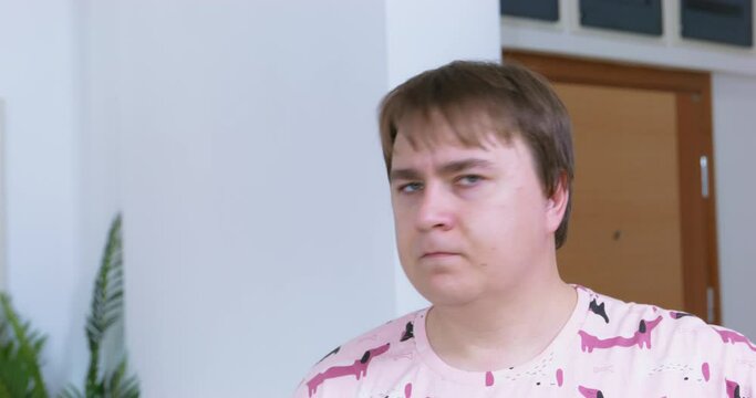 Portrait of chubby man in pajamas looks displeased, frowns, shakes his head in act of kindness, is angry. Innocent father sternly scolds children for prank. Love, strict family upbringing, discipline