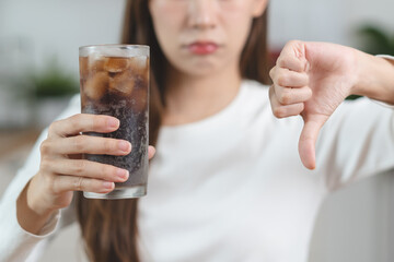 Close-up hands of a Person holding a soda sugar glass and showing a hand sign stop to diet sugar...