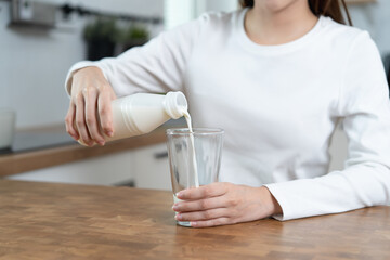Close-up hands of Person pouring milk into a glass on the table