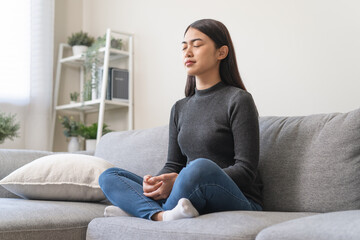 Young woman sitting on the floor and doing meditation practice mindfulness at home