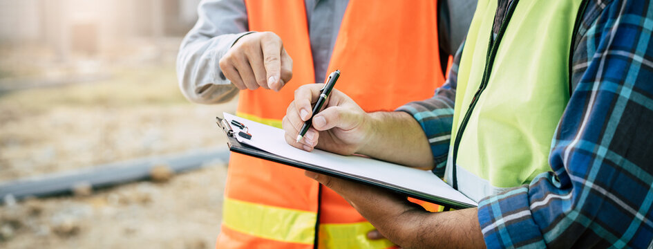 Builder engineer and supervisor consultant inspection job plan  concept, Asian contractor and foreman looking blueprint in computer laptop and checking process plan of factory warehouse construction