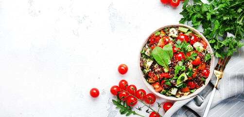 Quinoa tabbouleh salad with red cherry tomatoes, orange paprika, avocado, cucumbers and parsley. Traditional Middle Eastern and Arabic dish. White table background, top view banner - obrazy, fototapety, plakaty
