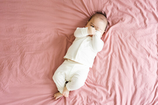 image of a newborn baby lying on a pink bed