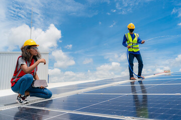 Professional worker cleaning solar panels with brush and washing with water on roof structure of building factory. Technician using mop to clean the dirty and dust, green electricity energy technology