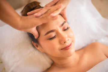 Fototapeta na wymiar Professional masseuse massaging the head of a happy beautiful asian client.