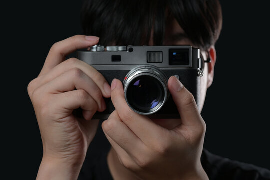photographer take pictures Snapshot with camera vintage rangefinder. korean young hand holding with camera looking through lens.Concept for photographing articles Professionally.