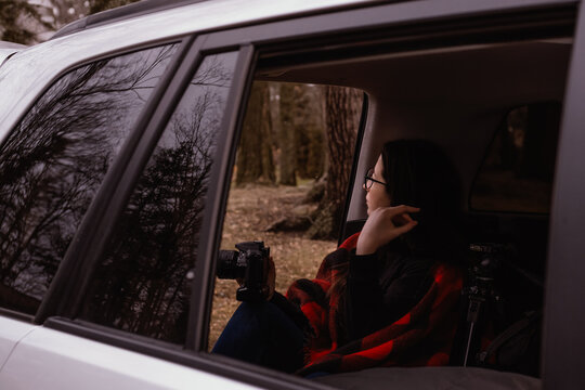 woman taking picture and looking the nature sitting in the back of a car