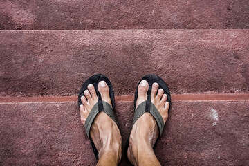 High Angle View of Low Section of man with sandals standing on Staircase. Illustration for Single, freedom, simple life, solitude, confused decision making, solo traveling, starting a business.