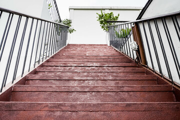 Fototapeta premium Red cement steps in the city Closeup concrete staircase with railing, old staircase detail, abstract stone staircase background.