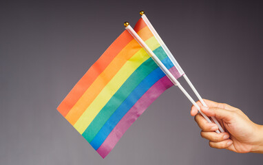 Rainbow flags showing in hand against a black background