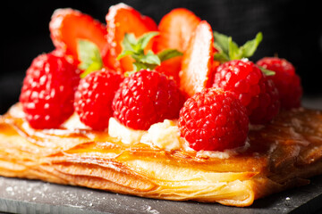 Delicious mixed berry Danish with custard, raspberries, and strawberries dusted with icing sugar and decorated with mint leaves.