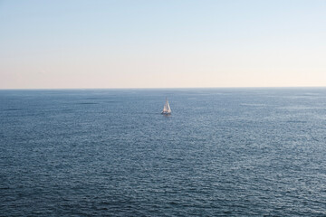 A yacht boat sailing on a vast blue ocean with a sunny sky