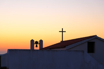 Cross and bell on a chapel in a beautiful sunset sky