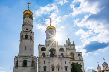 Fototapeta na wymiar Ivan the Great Bell Tower, with Assumption Belfry on the right in Moscow Kremlin. Blue sky background with sunbeams