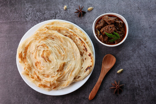 Beef curry with Kerala parathas porotta roti parotta barotta naan layered flatbread made from maida or whole wheat flour. Eat with spicy Asian chicken beef egg curry gravy. Indian food.