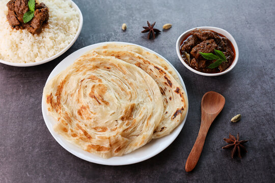 Beef curry with Kerala parathas porotta roti parotta barotta naan layered flatbread made from maida or whole wheat flour. Eat with spicy Asian chicken beef egg curry gravy. Indian food.