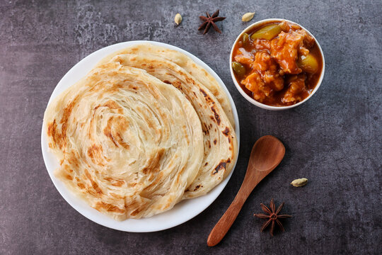 Chilly chicken with Kerala parathas porotta roti parotta barotta naan layered flatbread made from maida whole wheat flour. Eat with spicy Asian chicken beef egg curry gravy. Indian food.