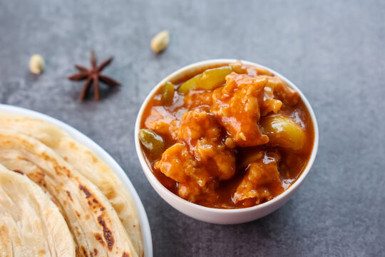 Chilli chicken with Kerala parathas porotta roti parotta barotta naan layered flatbread made from maida whole wheat flour. Eat with spicy Asian chicken beef egg curry gravy. Indian food.