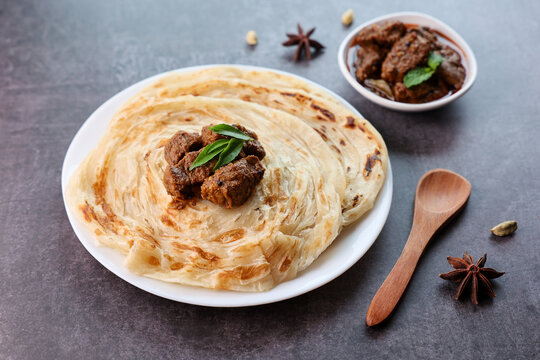 Beef curry with Kerala parathas porotta roti parotta barotta naan layered flatbread made from maida or whole wheat flour. Eat with spicy Asian chicken beef egg curry gravy. Indian food.