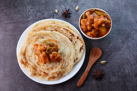 Chilli chicken with Kerala parathas porotta roti parotta barotta naan layered flatbread made from maida whole wheat flour. Eat with spicy Asian chicken beef egg curry gravy. Indian food.