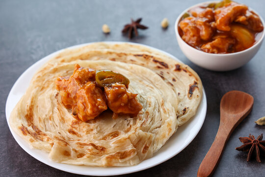 Chilly chicken with Kerala parathas porotta roti parotta barotta naan layered flatbread made from maida whole wheat flour. Eat with spicy Asian chicken beef egg curry gravy. Indian food.