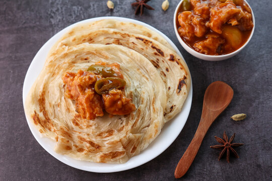 Chilly chicken with Kerala parathas porotta roti parotta barotta naan layered flatbread made from maida whole wheat flour. Eat with spicy Asian chicken beef egg curry gravy. Indian food.